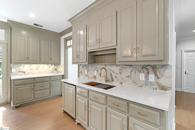 kitchen with light hardwood / wood-style floors, tasteful backsplash, ornamental molding, gray cabinets, and sink