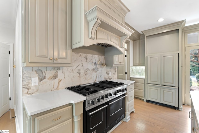 kitchen with range with two ovens, custom exhaust hood, light hardwood / wood-style flooring, and tasteful backsplash