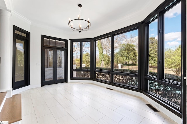 interior space featuring french doors, decorative columns, and a chandelier