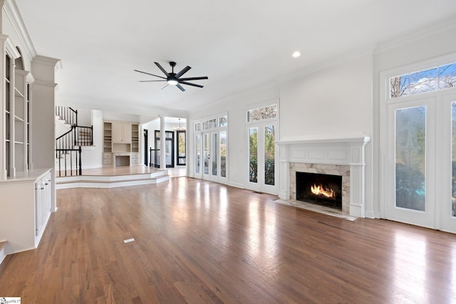 unfurnished living room with ornamental molding, light hardwood / wood-style flooring, ceiling fan with notable chandelier, and a fireplace