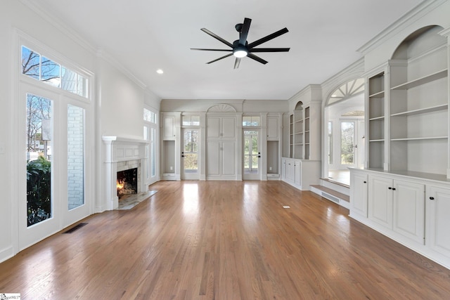 unfurnished living room with ceiling fan, a fireplace, a healthy amount of sunlight, and hardwood / wood-style flooring