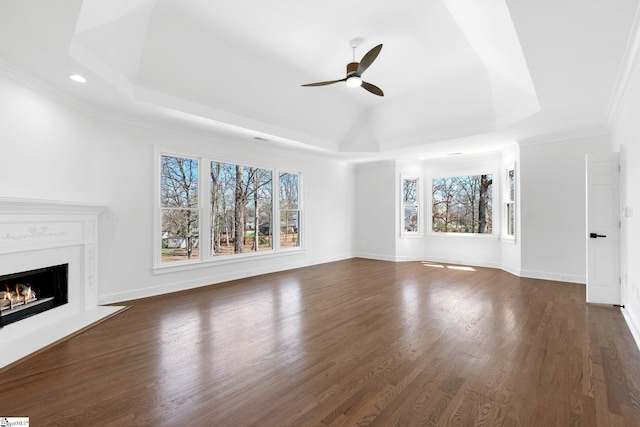 unfurnished living room with plenty of natural light, dark wood-type flooring, and a raised ceiling