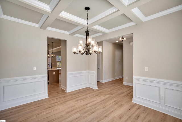 unfurnished dining area featuring sink, beamed ceiling, coffered ceiling, light wood-type flooring, and a chandelier