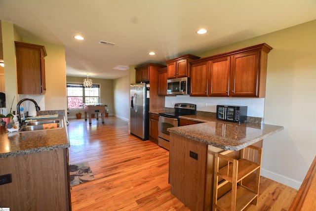 kitchen featuring stainless steel appliances, a kitchen breakfast bar, sink, and light hardwood / wood-style floors