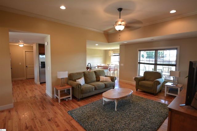 living room with ornamental molding, wood-type flooring, and ceiling fan