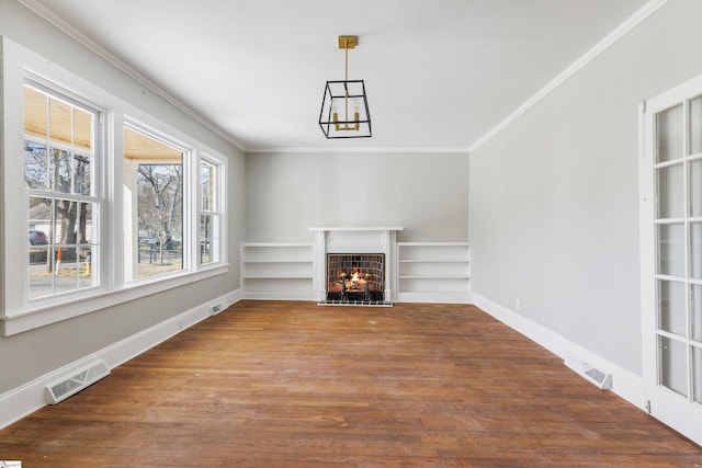 unfurnished living room featuring crown molding, built in shelves, and dark wood-type flooring