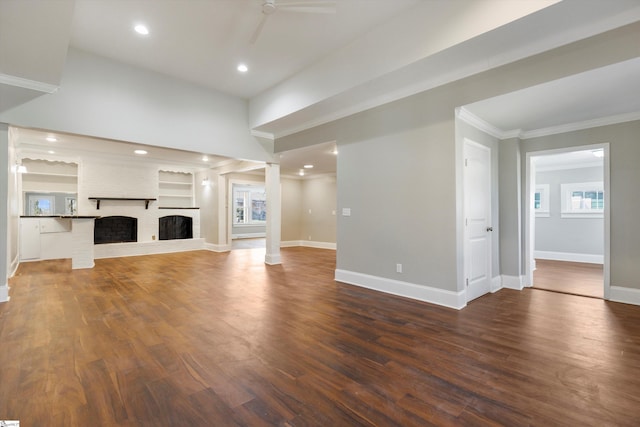 unfurnished living room featuring a fireplace, ceiling fan, dark wood-type flooring, built in shelves, and ornate columns