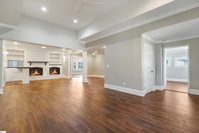 unfurnished living room with ceiling fan, dark wood-type flooring, a brick fireplace, and ornate columns