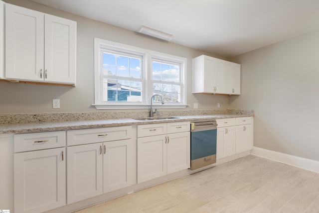 kitchen with dishwasher, white cabinetry, sink, and light hardwood / wood-style floors