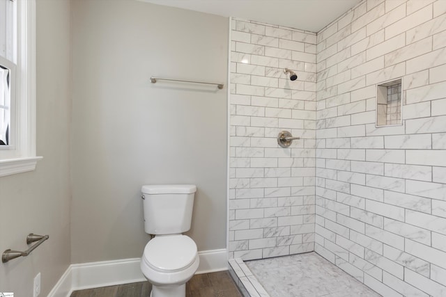 bathroom with toilet, hardwood / wood-style flooring, and tiled shower