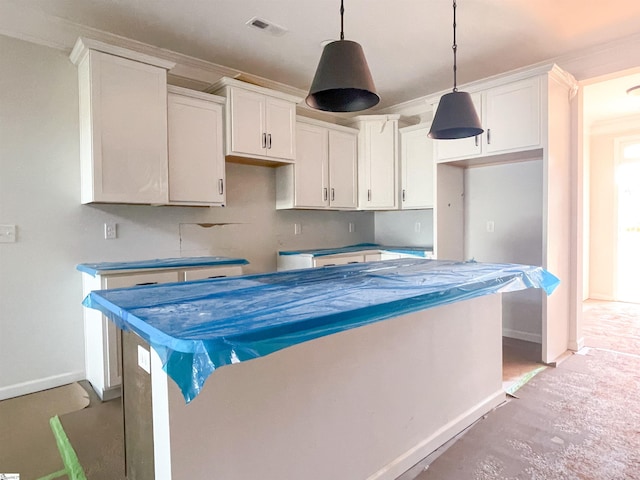 kitchen with hanging light fixtures, ornamental molding, and white cabinets