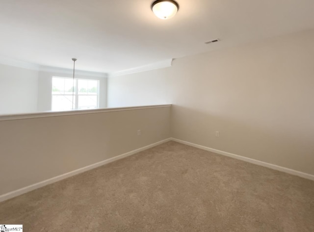 carpeted spare room featuring crown molding