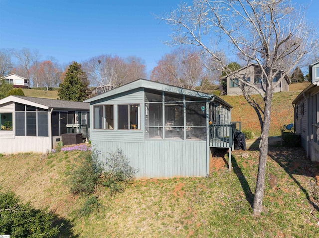 rear view of house with a lawn and a sunroom