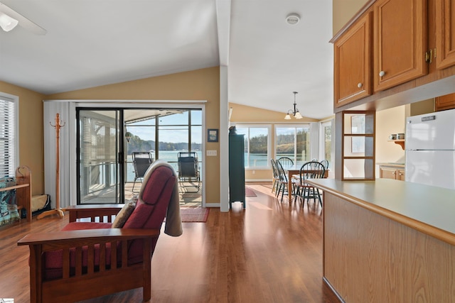 interior space featuring lofted ceiling, a water view, wood-type flooring, and ceiling fan with notable chandelier