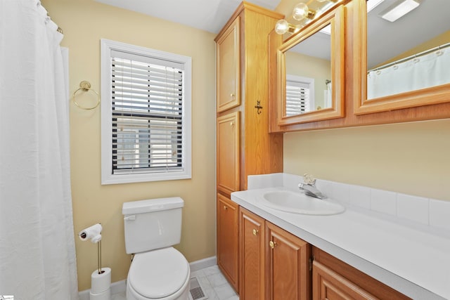 bathroom with toilet, large vanity, and tile flooring