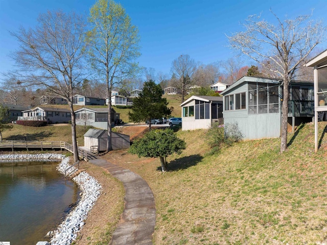 view of yard with a sunroom, a water view, and a shed