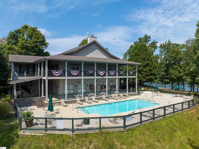 rear view of property with a balcony, a patio area, and a community pool