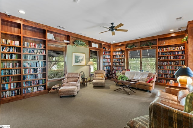 living room with carpet floors, wooden walls, built in features, and ceiling fan