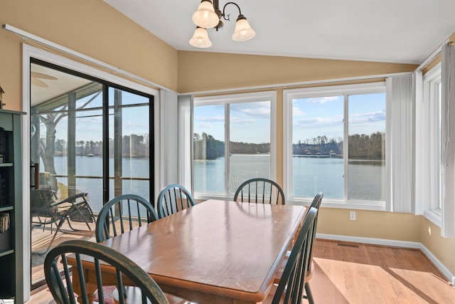 dining room featuring a water view, a notable chandelier, and a healthy amount of sunlight