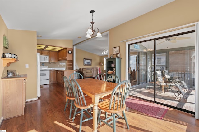 dining space with dark wood-type flooring, vaulted ceiling, and ceiling fan with notable chandelier