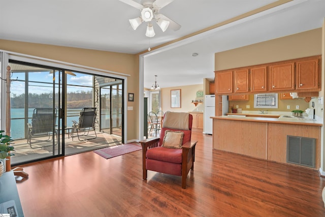 sitting room featuring a water view, wood-type flooring, ceiling fan with notable chandelier, sink, and vaulted ceiling