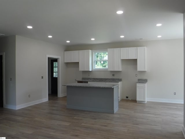 kitchen featuring light hardwood / wood-style floors, white cabinetry, light stone countertops, and a kitchen island