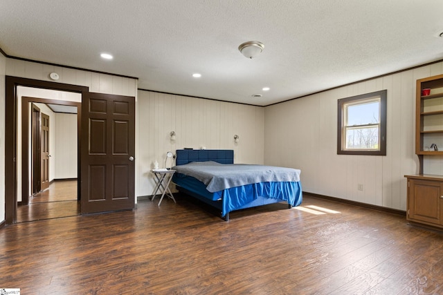 bedroom with dark hardwood / wood-style flooring, wooden walls, and a textured ceiling