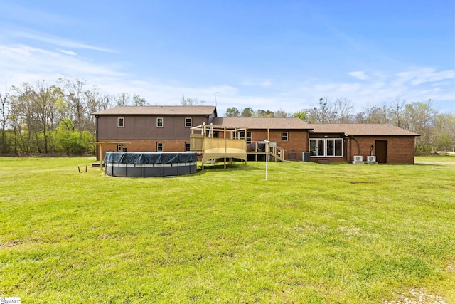 rear view of house featuring a covered pool and a lawn