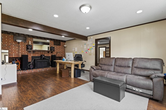 living room with a textured ceiling, dark wood-type flooring, brick wall, and beamed ceiling