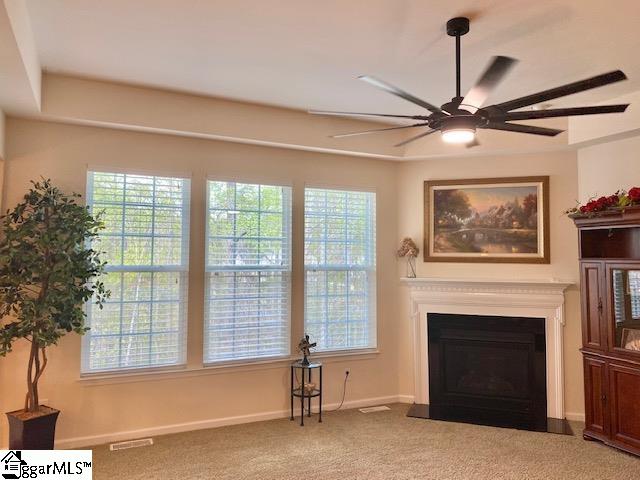 living area with ceiling fan, carpet flooring, and a healthy amount of sunlight