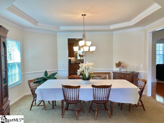 dining space with a raised ceiling, an inviting chandelier, and a wealth of natural light