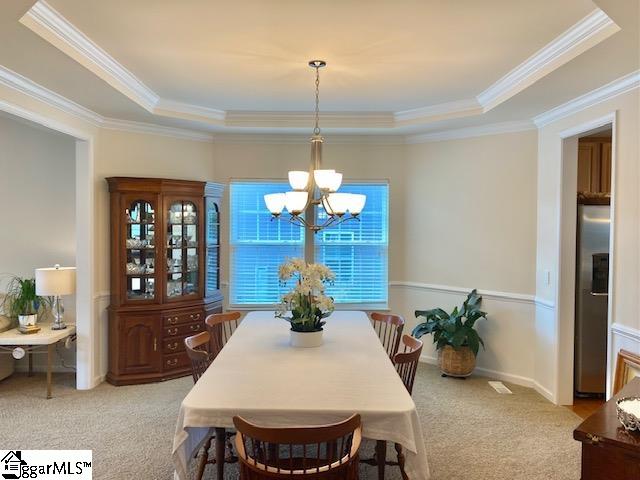 dining room featuring a raised ceiling, a notable chandelier, and crown molding