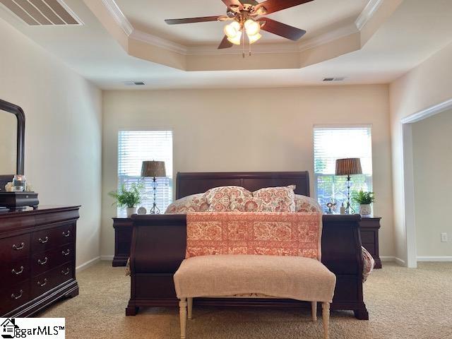 bedroom featuring ornamental molding, light colored carpet, ceiling fan, and a tray ceiling