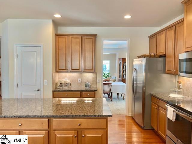 kitchen featuring backsplash, stove, dark stone countertops, and light wood-type flooring