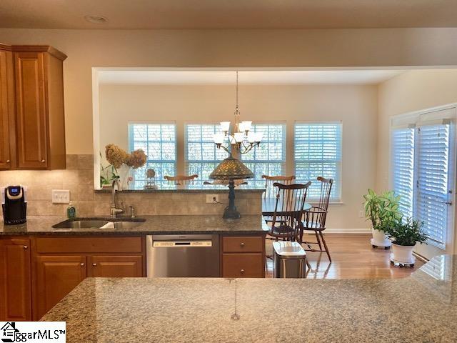 kitchen featuring dishwasher, light hardwood / wood-style floors, dark stone countertops, and sink