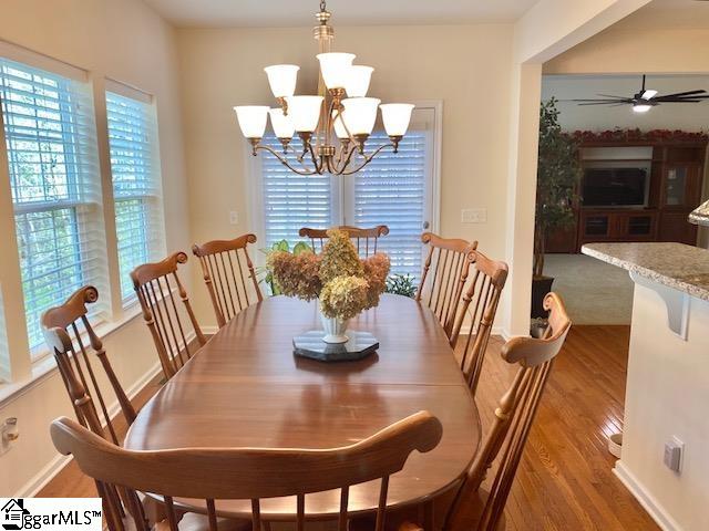 dining space with a wealth of natural light, ceiling fan with notable chandelier, and hardwood / wood-style flooring