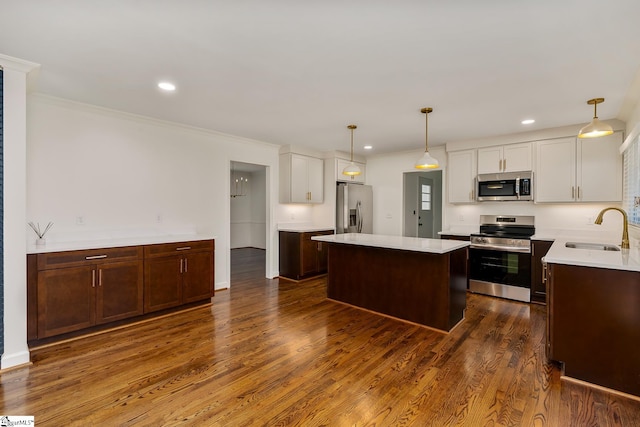 kitchen featuring appliances with stainless steel finishes, dark hardwood / wood-style floors, a center island, pendant lighting, and sink