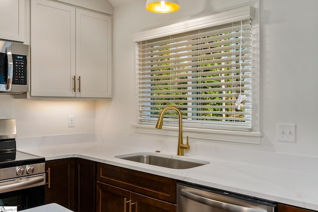 kitchen featuring appliances with stainless steel finishes, sink, white cabinetry, and dark brown cabinetry