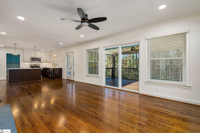 unfurnished living room with ceiling fan, dark wood-type flooring, sink, and crown molding