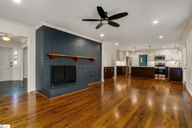 unfurnished living room featuring crown molding, dark hardwood / wood-style floors, a brick fireplace, and ceiling fan