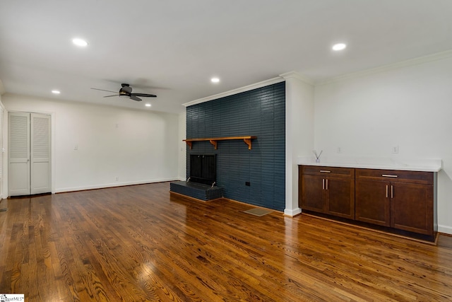 unfurnished living room with a fireplace, ornamental molding, ceiling fan, and dark hardwood / wood-style flooring