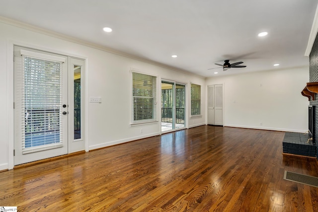 unfurnished living room featuring a brick fireplace, ceiling fan, dark hardwood / wood-style floors, and crown molding