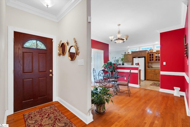 foyer with a notable chandelier, crown molding, light hardwood / wood-style floors, and a wealth of natural light