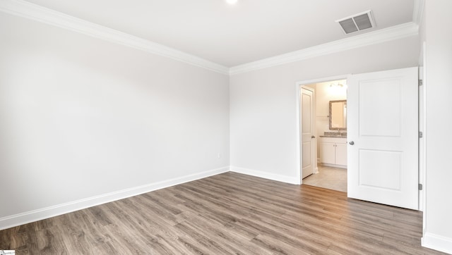 unfurnished bedroom featuring hardwood / wood-style flooring, crown molding, and ensuite bathroom