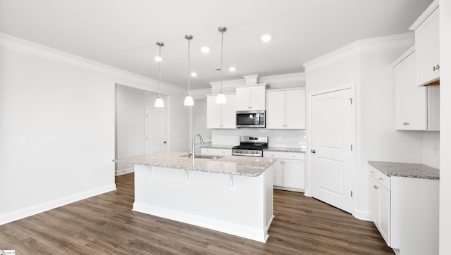 kitchen featuring appliances with stainless steel finishes, decorative light fixtures, sink, white cabinets, and light stone countertops