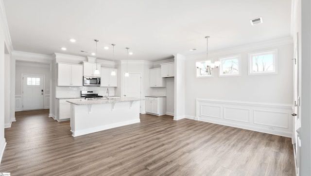 kitchen featuring pendant lighting, appliances with stainless steel finishes, a kitchen island with sink, and white cabinets