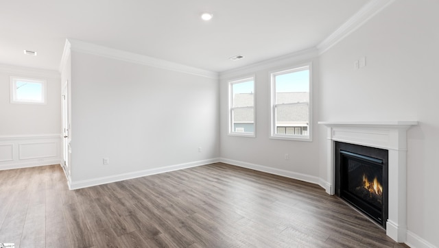 unfurnished living room featuring hardwood / wood-style flooring, ornamental molding, and a wealth of natural light