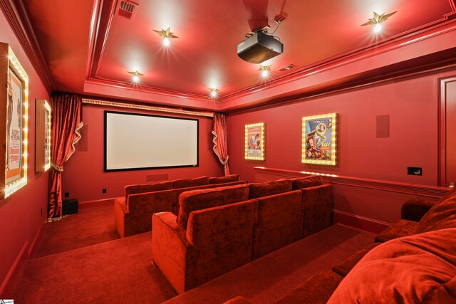 cinema room featuring ornamental molding, a tray ceiling, and carpet