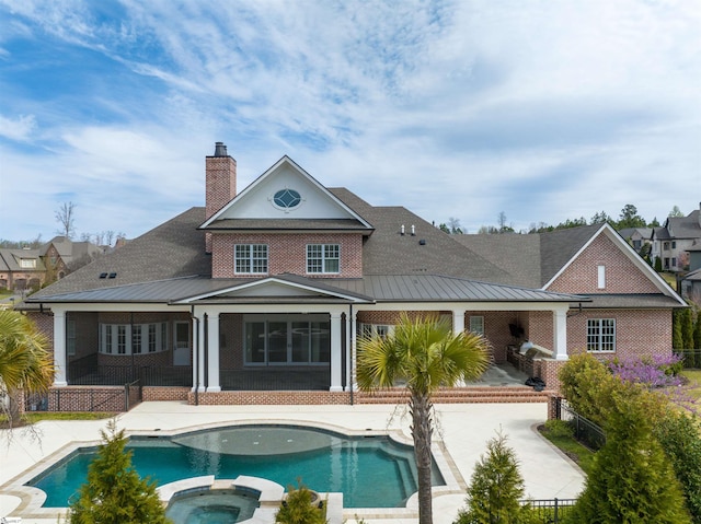 rear view of property featuring a swimming pool with hot tub and a patio