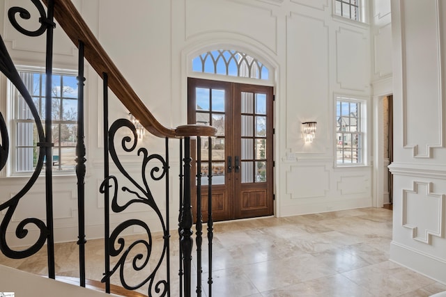 tiled foyer featuring a high ceiling, french doors, and a wealth of natural light